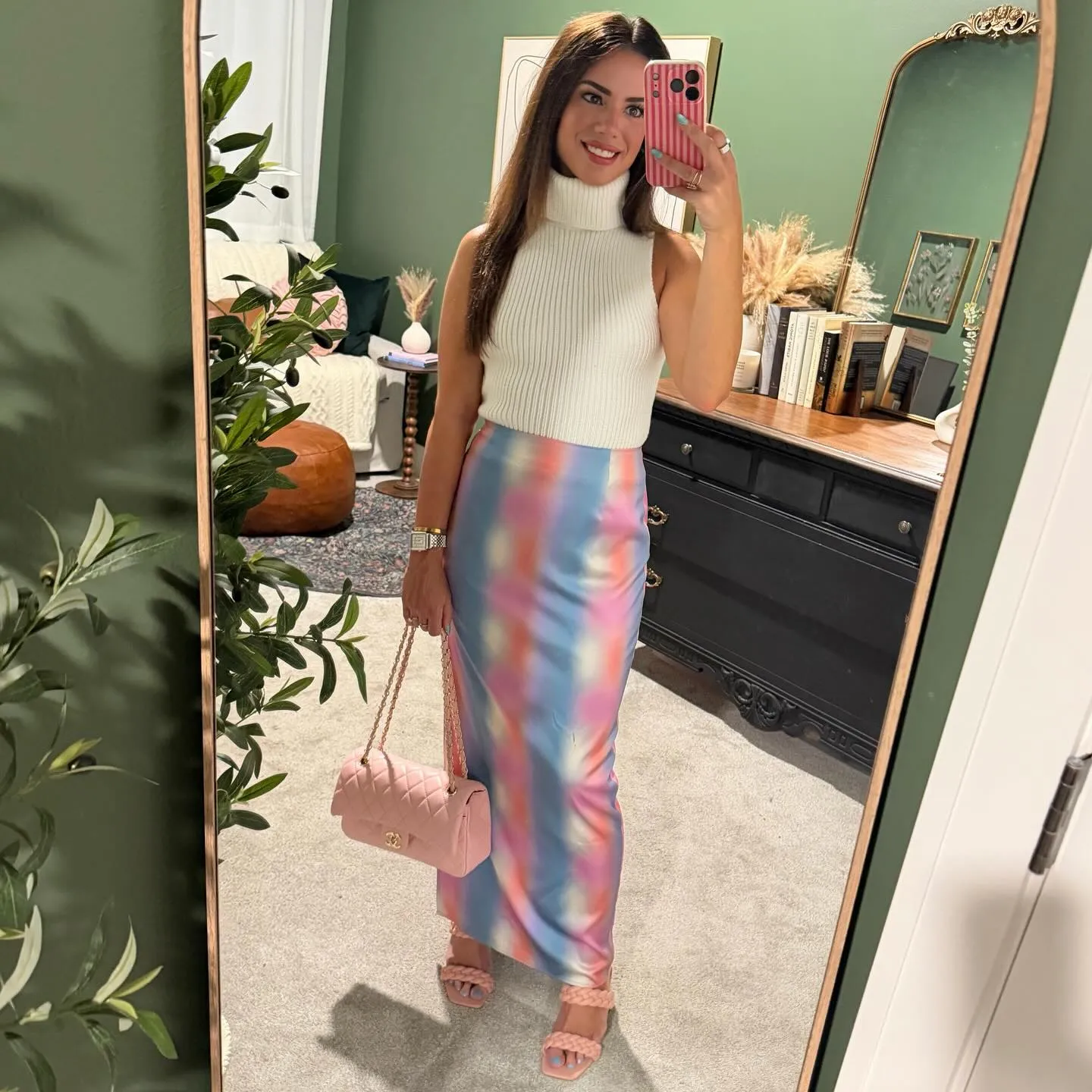 Susanne in a white sleeveless knit turtleneck and pastel rainbow watercolor maxi skirt with a pink quilted bag and pink braided-strap heels